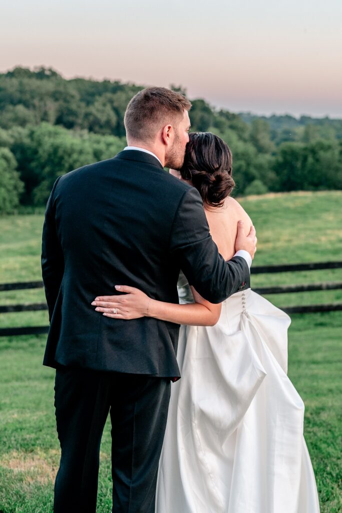 A groom kissing his bride as they watch the sunset during their Loudoun County wedding