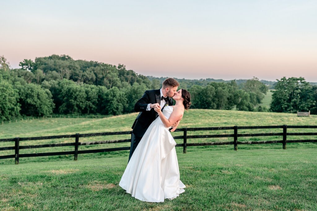 A groom dips his bride and kisses her at sunset during Shadow Creek wedding portraits