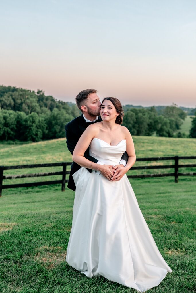 A groom kisses his bride on the cheek after their St. Francis de Sales wedding
