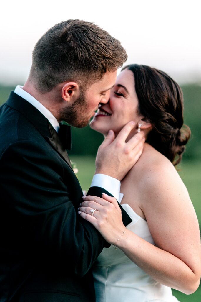 A bride and groom smiling as they go for a kiss at sunset on their Loudoun County wedding day