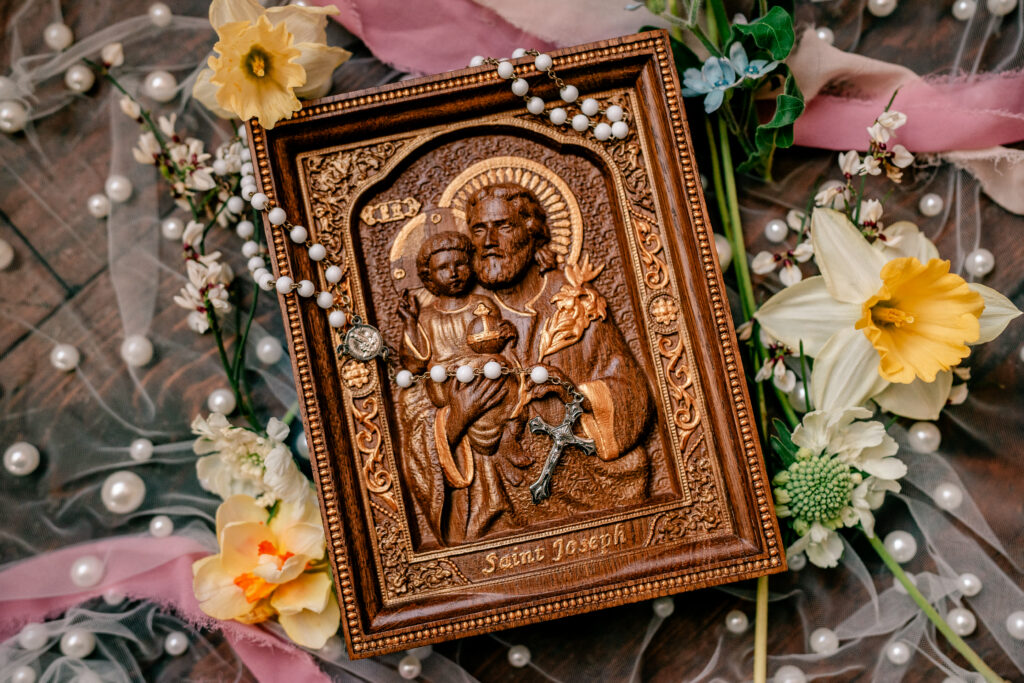 A St. Joseph carving with a rosary draped over it by a Catholic wedding photographer
