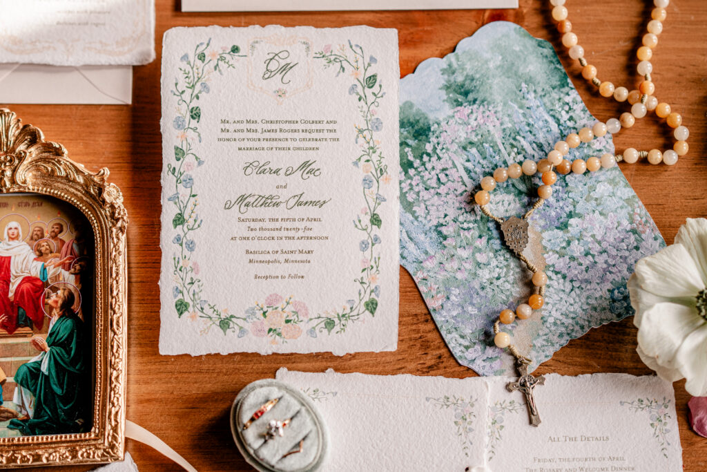 A Monet-inspired wedding invitation with a rosary draped over top