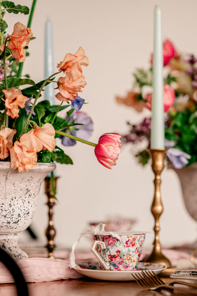 A pink tulip hanging over top of a pink floral tea cup for a Catholic wedding photographer