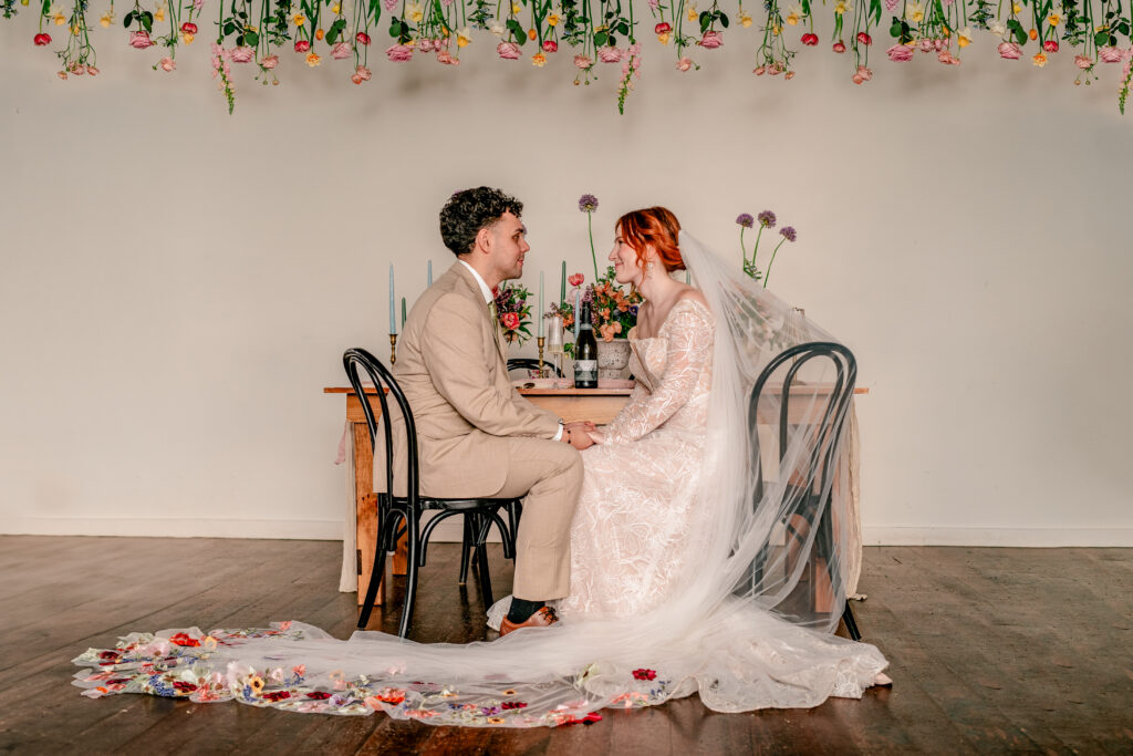 A bride and groom holding hands at a table decorated with flowers for their Catholic wedding photographer