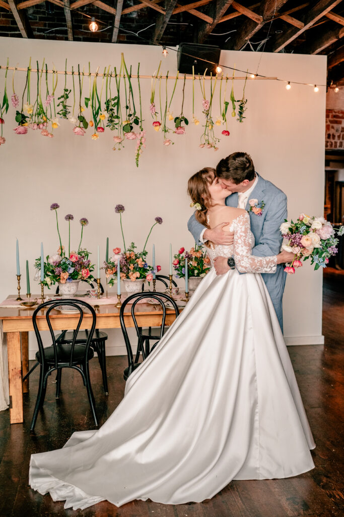 A bride and groom sharing a kiss in front of their sweetheart table for their Northern VA wedding photographer