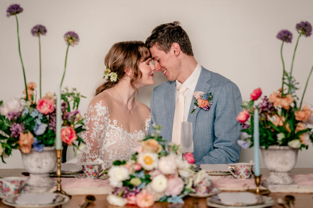 A bride and groom posing forehead to forehead seated at their reception during a tea party wedding