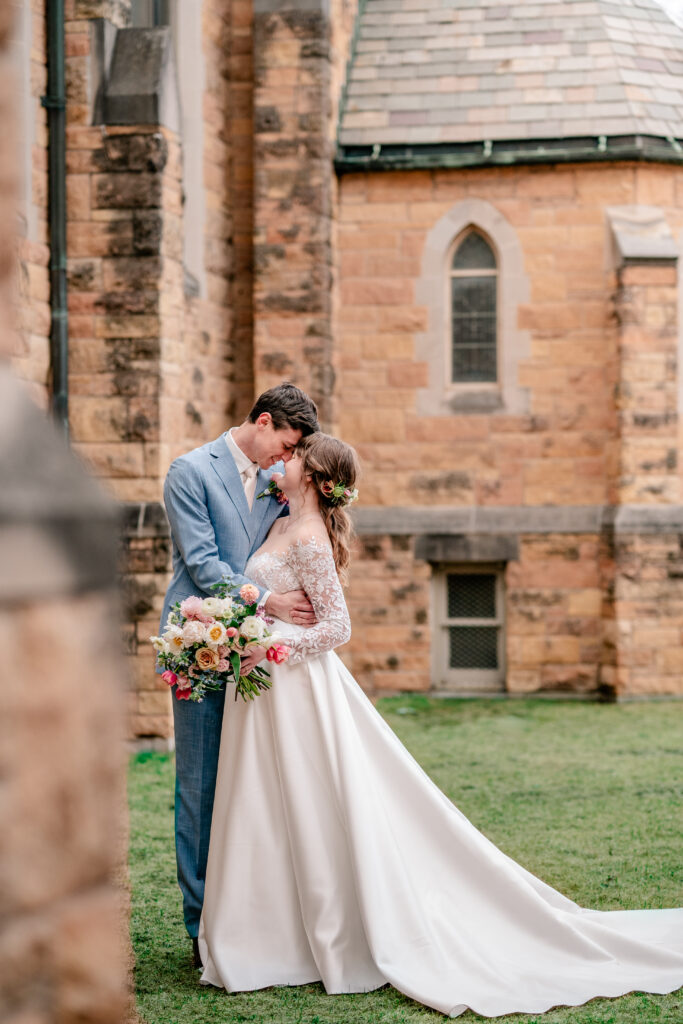 A bride and groom posed romantically outside their church before their tea party wedding
