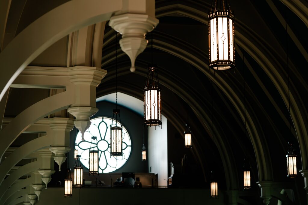 Pendant lights in a church hanging in front of a rose window