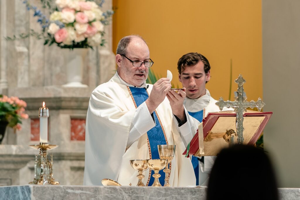 A priest holding up the Eucharist during a Catholic wedding