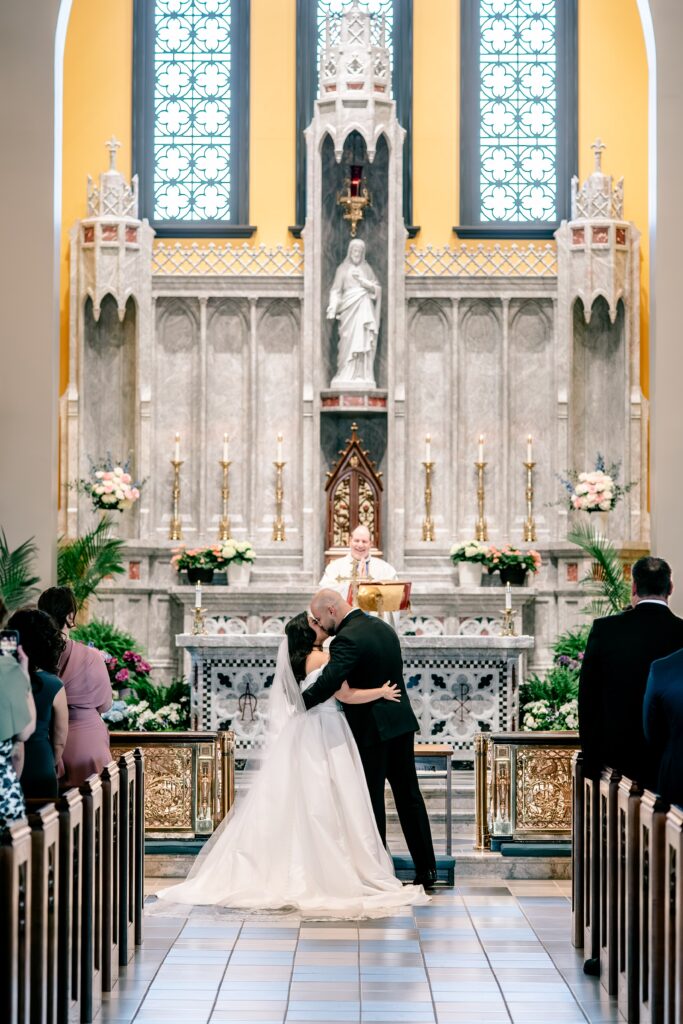 A bride and groom sharing their first kiss as husband and wife during their wedding at Corpus Christi Catholic Church in Aldie, VA