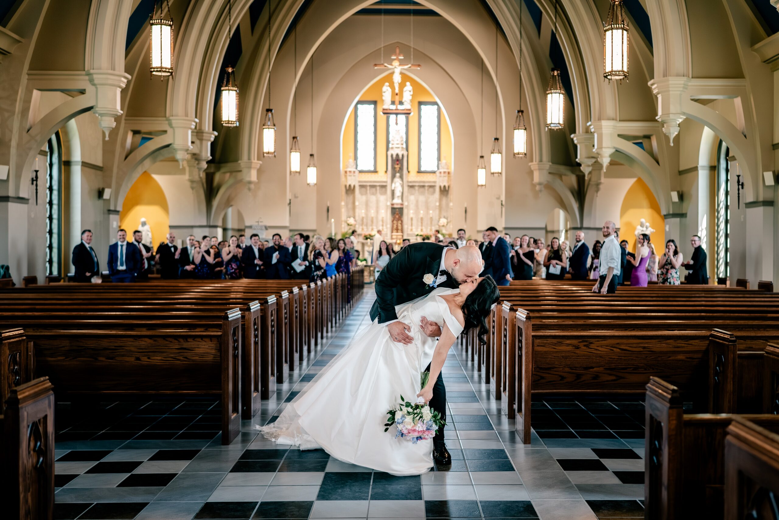 A bride and groom share a dip kiss at the end of their Loudoun County wedding at Corpus Christi Catholic Church