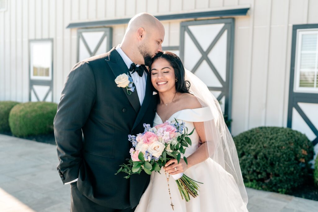 A groom kissing the top of his bride's head during their Shadow Creek wedding