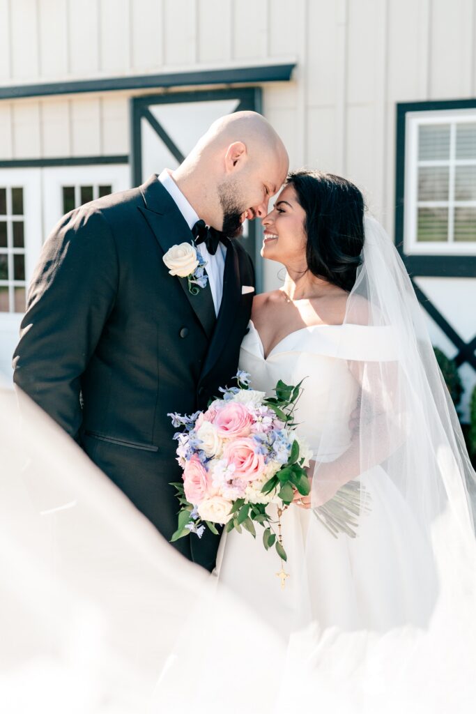 A bride and groom smiling at one another in the sun