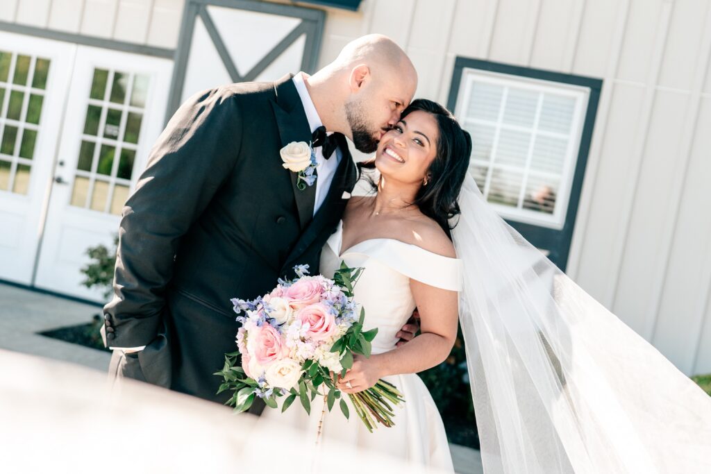 A groom kissing the cheek of his bride during their Shadow Creek wedding