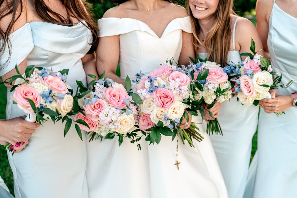 A group of bridesmaids holding their bouquets together with ivory, pink, and blue flowers during a Shadow Creek wedding