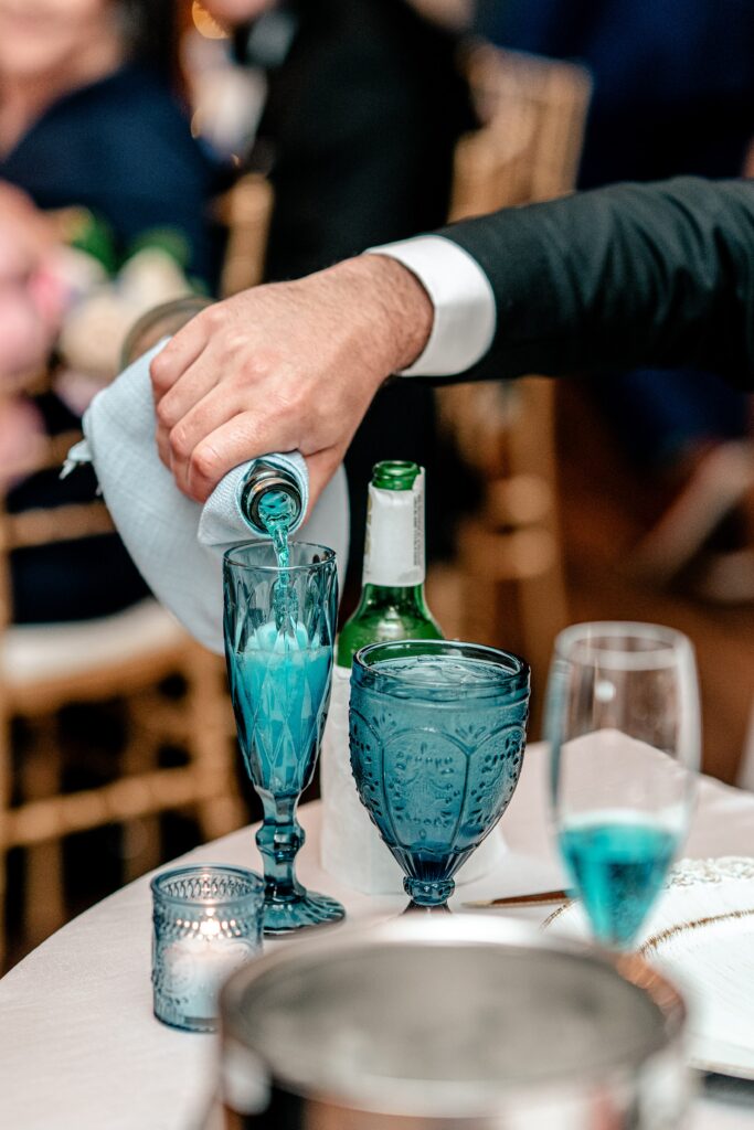 Someone pouring blue sparkling wine into a blue champagne flute at a Shadow Creek wedding