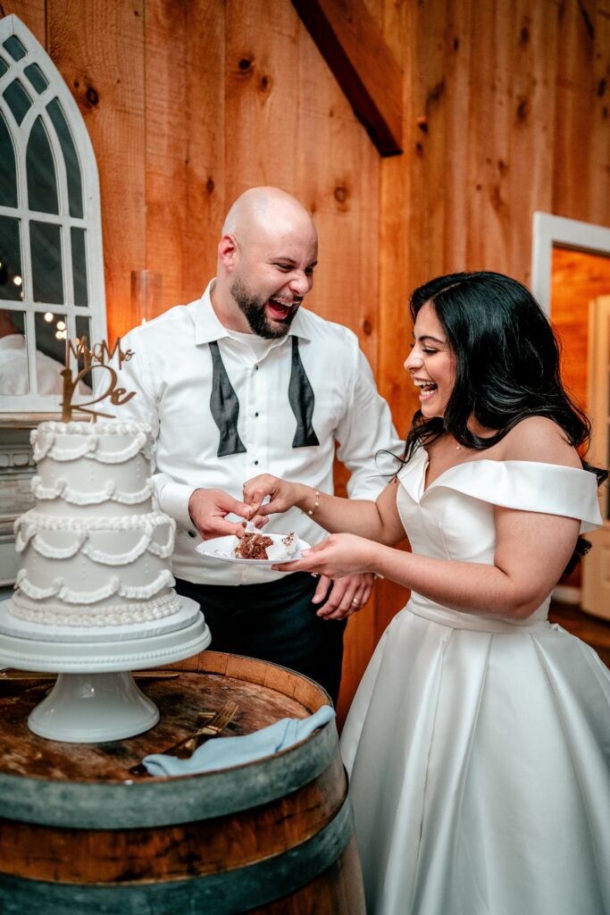 A bride and groom laughing during their cake cutting