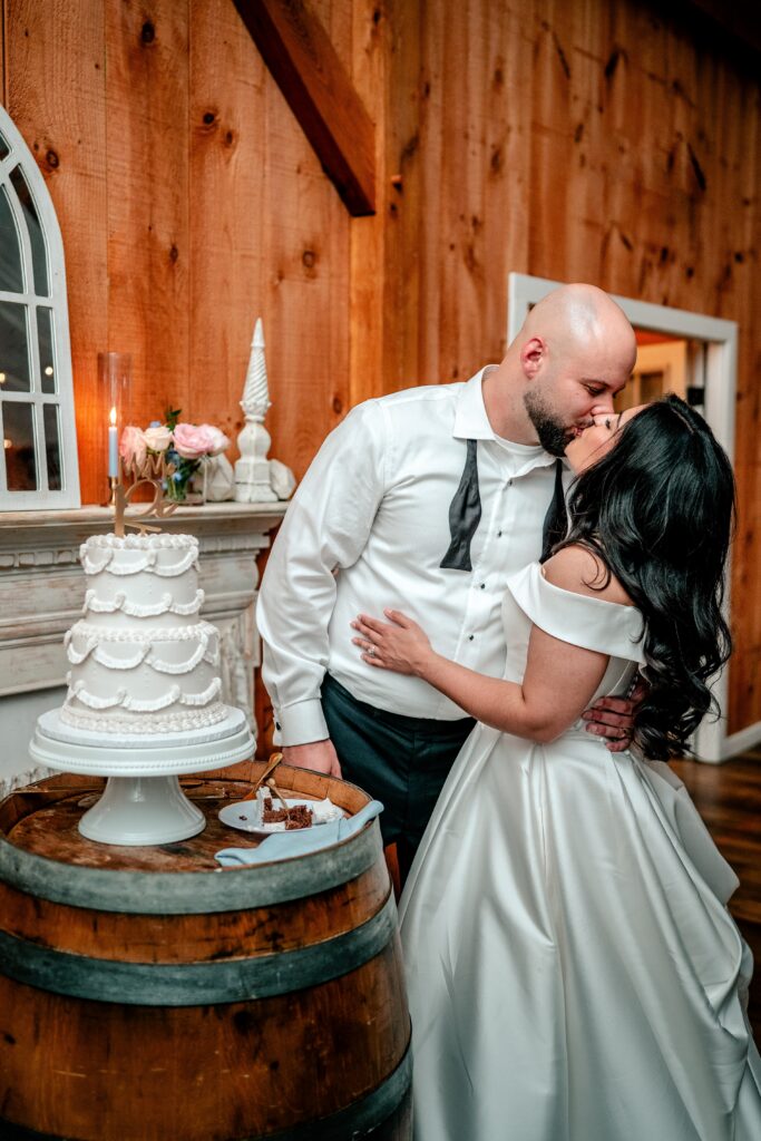 A bride and groom share a kiss during the cake cutting at their Loudoun County wedding
