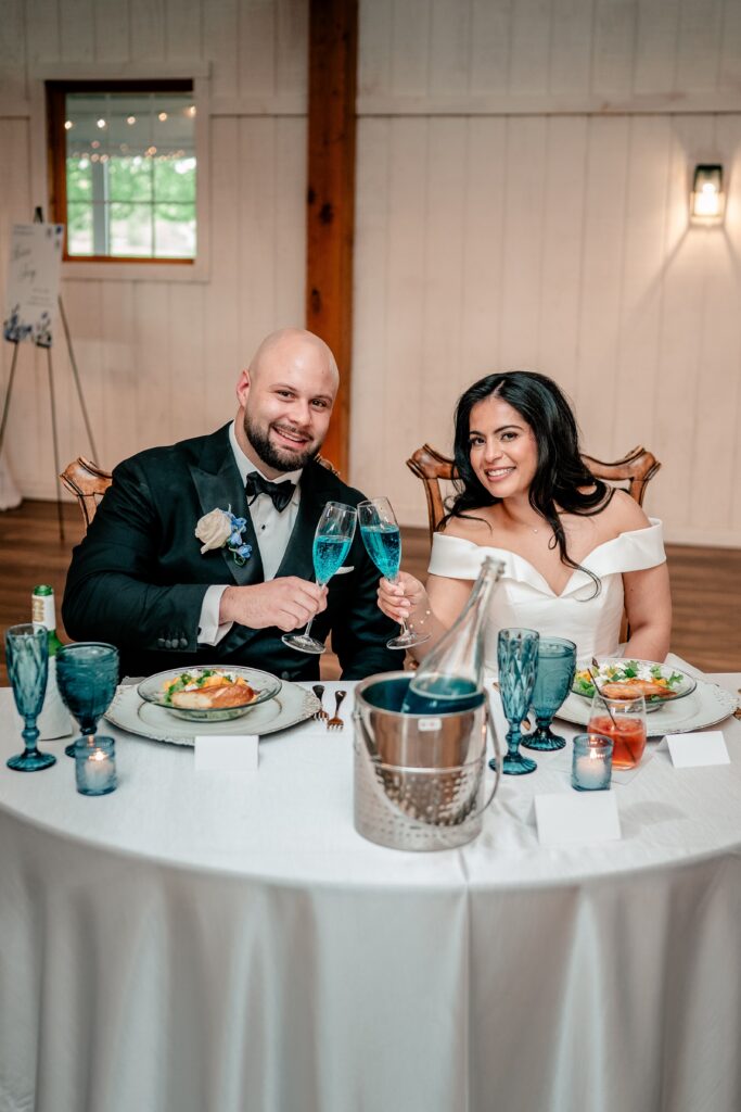 A bride and groom toasting with blue champagne and smiling for their Northern VA wedding photographer