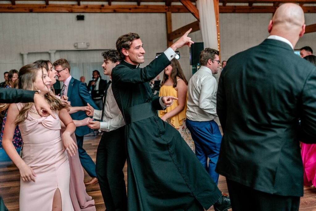 A priest dancing at a wedding with a Catholic wedding photographer