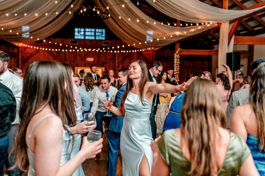 A bridesmaid dancing at a barn wedding reception