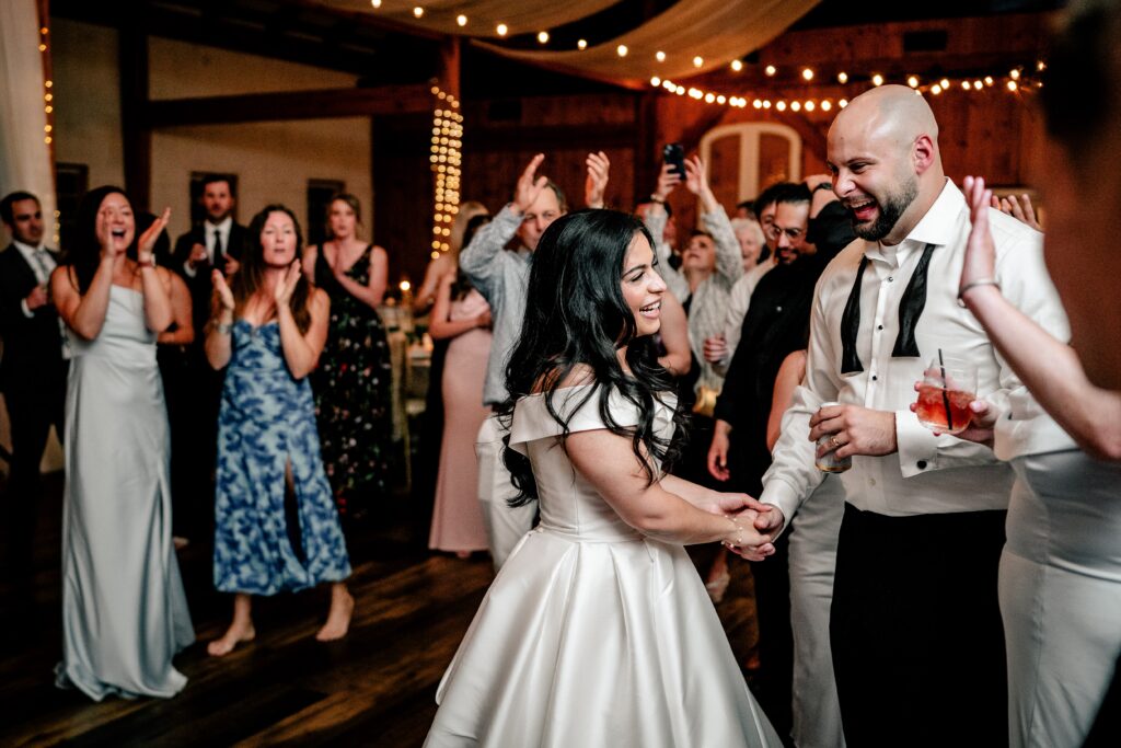 A bride and groom smiling and holding hands on the dance floor